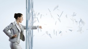 Young determined businesswoman breaking glass with karate punch